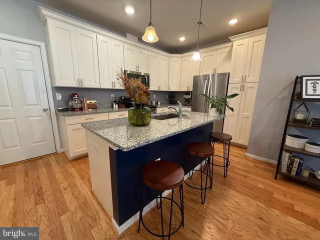 a kitchen with stainless steel appliances granite countertop a sink dishwasher and a refrigerator with wooden floor