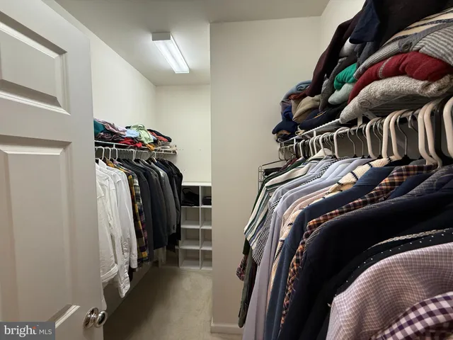 a view of walk in closet with clothes and shoes