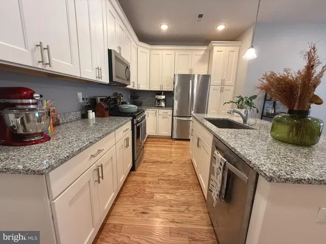 a large kitchen with granite countertop lots of counter space and stainless steel appliances