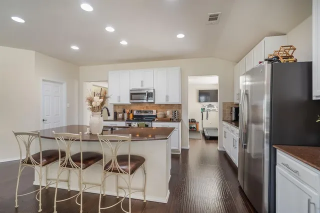 a kitchen with stainless steel appliances kitchen island granite countertop a refrigerator and a stove top oven
