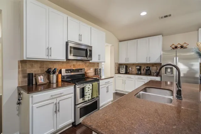 a kitchen with granite countertop a stove sink and microwave