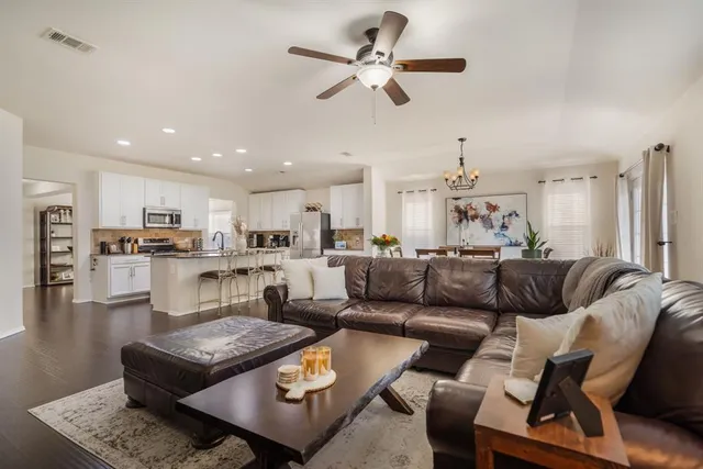 a living room with furniture kitchen view and a chandelier