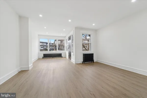 a view of a big room with wooden floor and windows