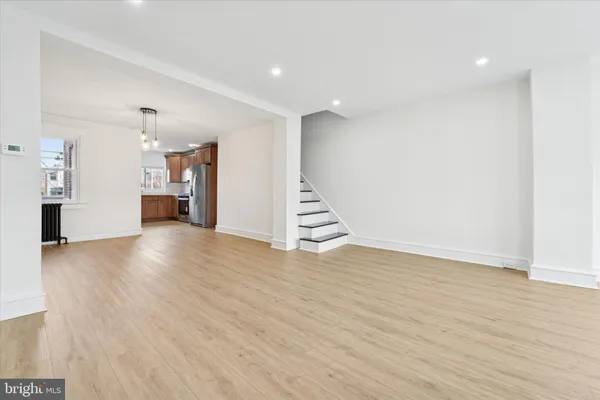a view of an empty room with wooden floor and stairs