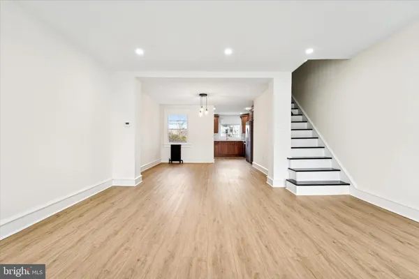 a view of an empty room with wooden floor and stairs