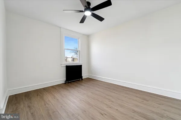 an empty room with wooden floor and ceiling fan