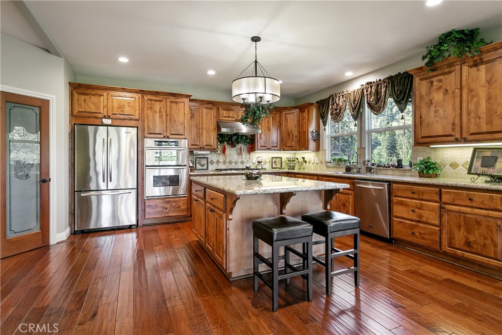 28449 Fresh Spring Lane Lake Arrowhead, CA 92352 - Photo 14 of 55 a kitchen with stainless steel appliances granite countertop a refrigerator a sink dishwasher a dining table and chairs with wooden floor