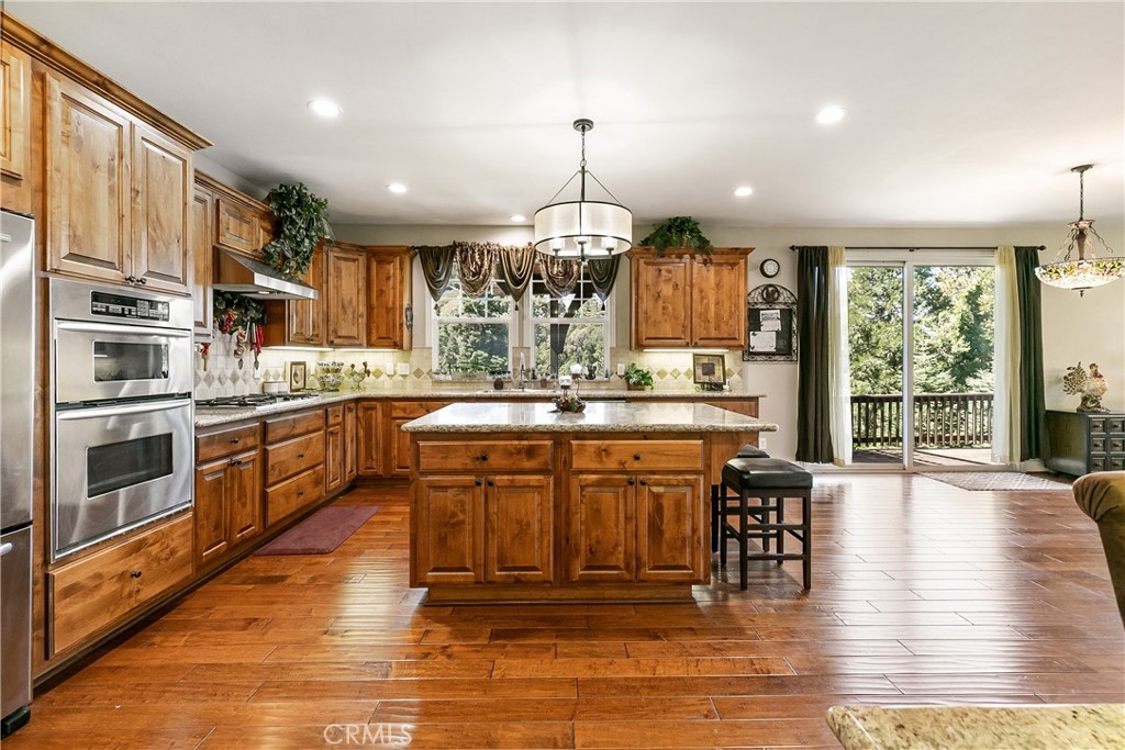 28449 Fresh Spring Lane Lake Arrowhead, CA 92352 - Photo 15 of 55 a kitchen with stainless steel appliances granite countertop a stove top oven a sink dishwasher a dining table and chairs with wooden floor