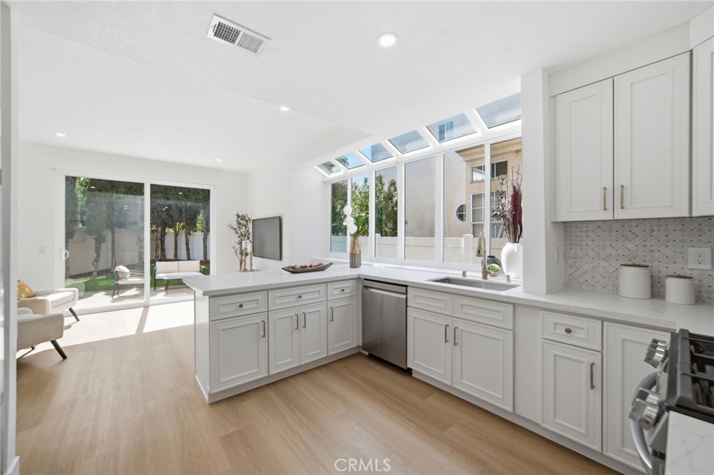32 Comiso Irvine, CA 92614 - Photo 10 of 22 a large white kitchen with cabinets and wooden floor