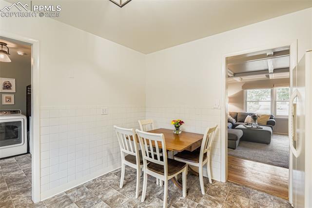 2462 Lafayette Road Colorado Springs, CO 80907 - Photo 9 of 22 Dining area featuring a wainscoted wall, washer / dryer, tile walls, and beam ceiling