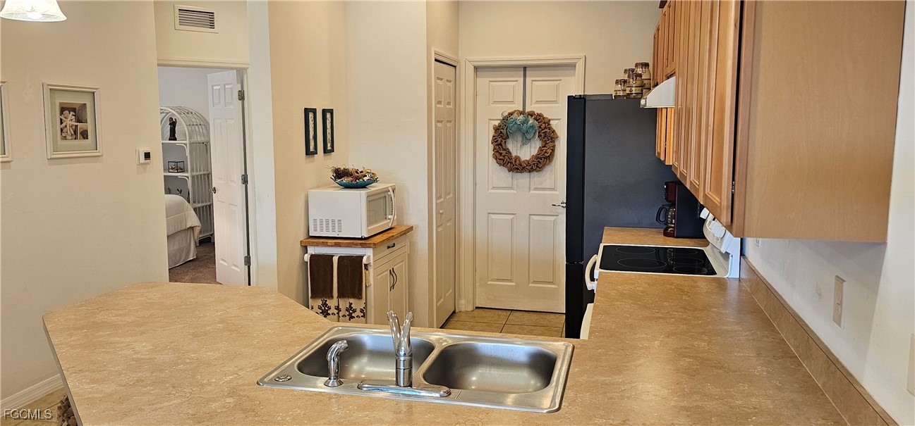 10788 Crossback Lane Lehigh Acres, FL 33936 - Photo 17 of 32 a kitchen with stainless steel appliances a sink and a refrigerator