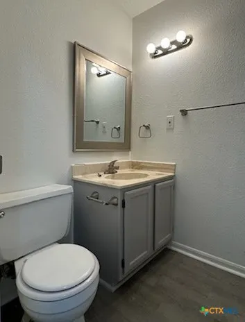 a bathroom with a granite countertop toilet sink and mirror
