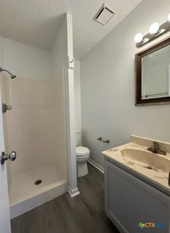 a bathroom with a granite countertop sink a toilet and shower