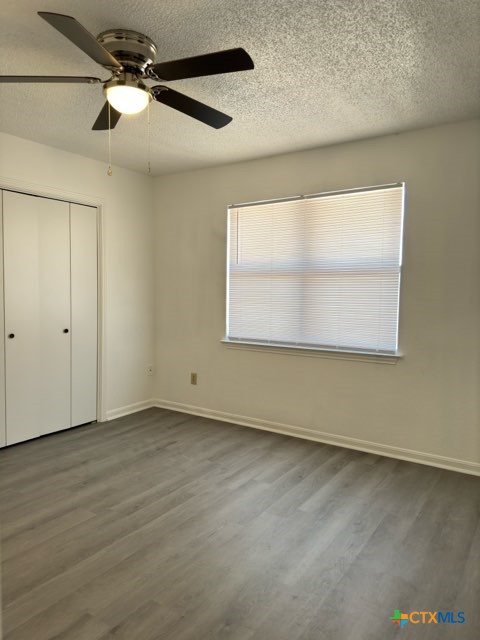1815 Cedarhill Drive, Unit C Killeen, TX 76543 - Photo 25 of 27 an empty room with wooden floor fan and windows