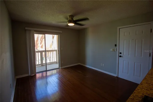 an empty room with wooden floor fan and windows