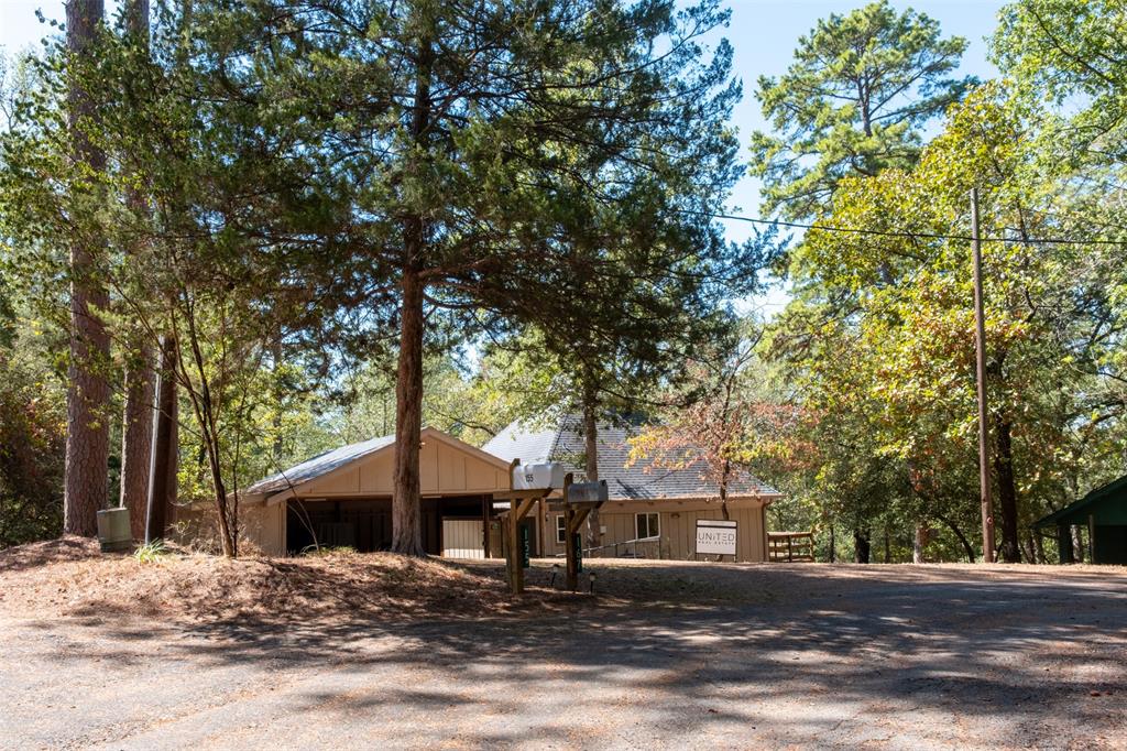 167 Blue Water Point Holly Lake Ranch, TX 75765 - Photo 2 of 27 Wood-sided residence with a covered carport and a sloped roofline, surrounded by mature trees
