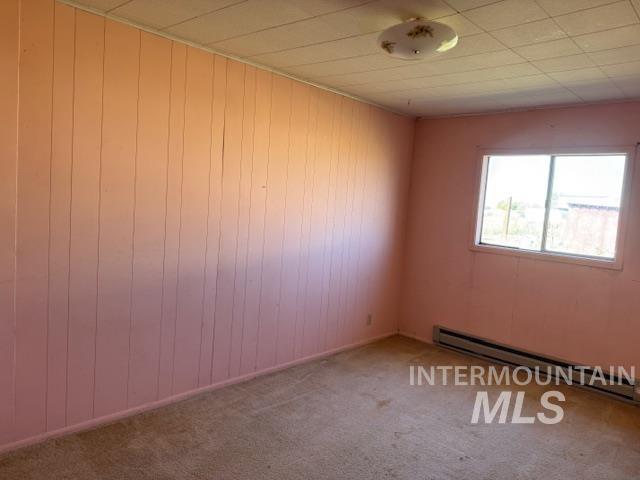 2900 West Sales Yard Road Emmett, ID 83617 - Photo 12 of 18 Spare room with baseboard heating, carpet floors, and wooden walls