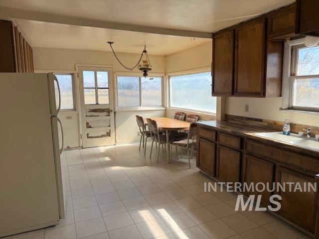 2900 West Sales Yard Road Emmett, ID 83617 - Photo 14 of 18 Kitchen with freestanding refrigerator, dark brown cabinets, dark countertops, pendant lighting, and light tile patterned floors