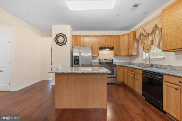 a kitchen with granite countertop a sink cabinets and wooden floor
