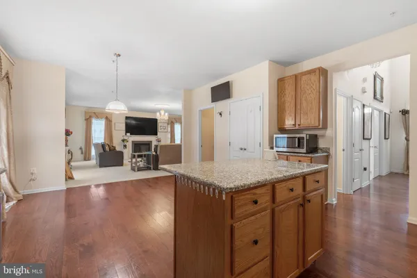 a kitchen with stainless steel appliances granite countertop a refrigerator a stove oven and white cabinets with wooden floors