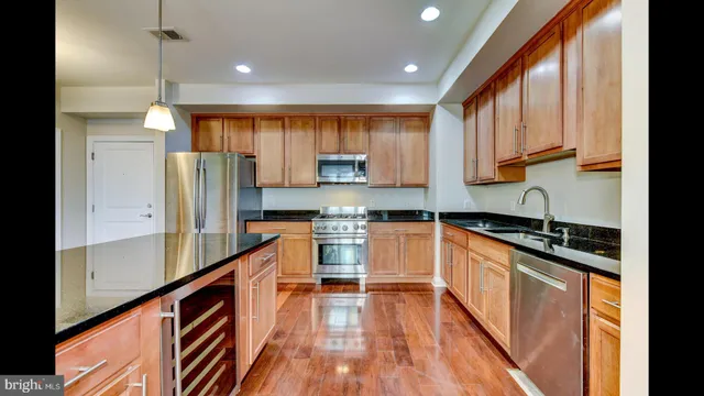 a kitchen with stainless steel appliances granite countertop a refrigerator a sink dishwasher a stove and white countertops with wooden floor