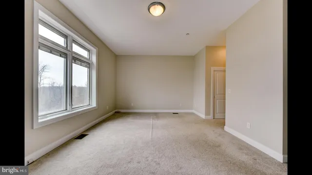 a view of an empty room with a window and a kitchen