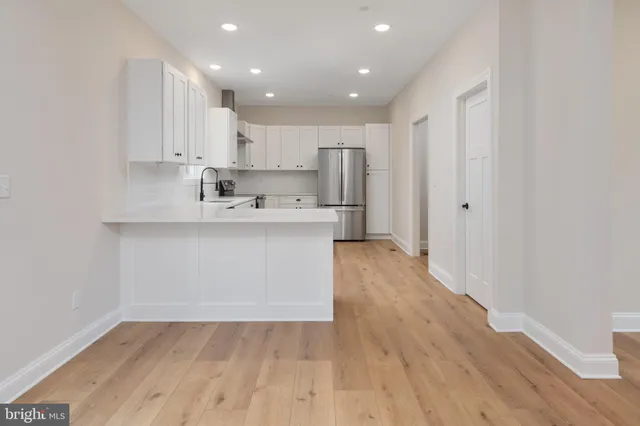 a kitchen with a sink a refrigerator and white cabinets