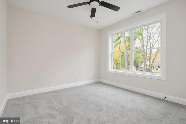 an empty room with a window and a ceiling fan