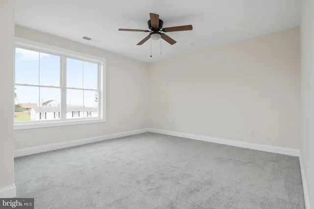 an empty room with a ceiling fan and carpet
