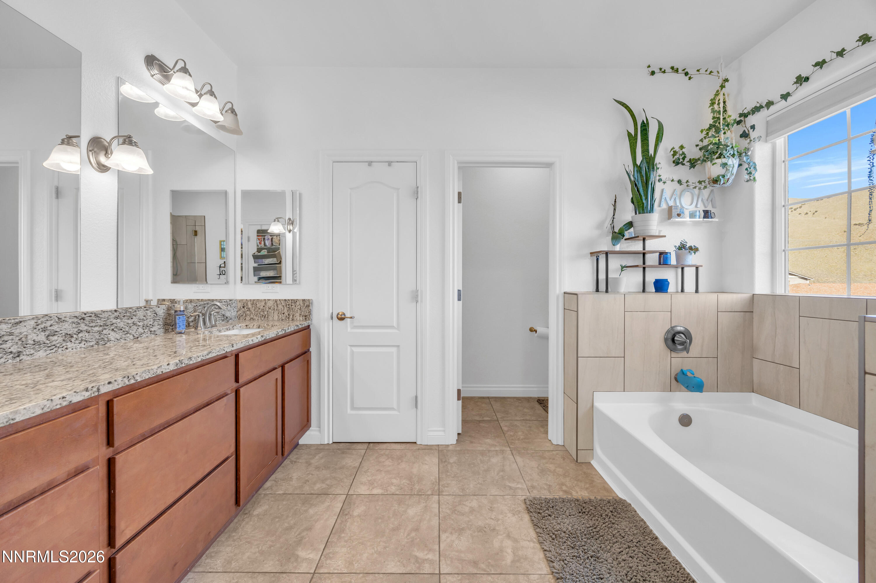 18648 Granite Peak Court Reno, NV 89508 - Photo 25 of 53 a bathroom with a granite countertop tub a sink and a large mirror