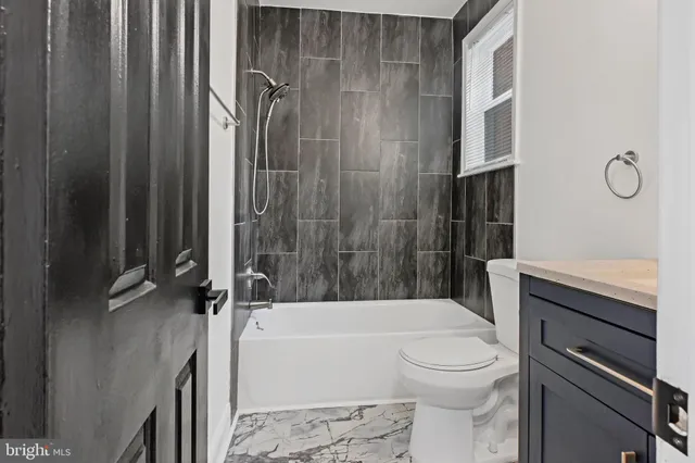a bathroom with a granite countertop bathtub shower sink vanity and toilet