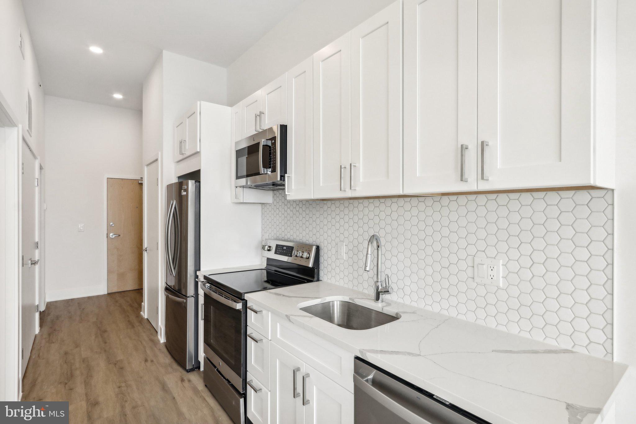 1622 Point Breeze Avenue, Unit 410 Philadelphia, PA 19145 - Photo 2 of 20 a kitchen with stainless steel appliances granite countertop a refrigerator and a stove top oven