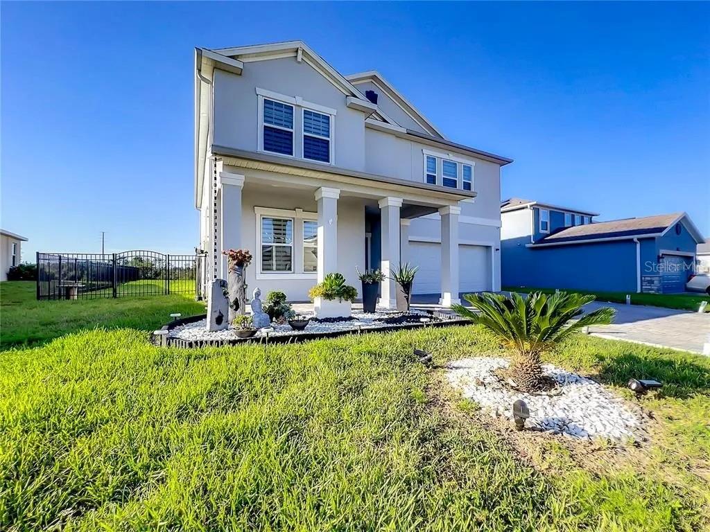 a view of a house with a big yard potted plants and a table and chair