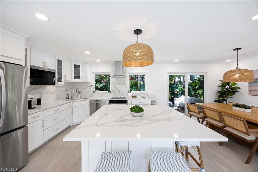 24 Rivard Road Naples, FL 34112 - Photo 12 of 29 a kitchen with stainless steel appliances a white table chairs and a refrigerator