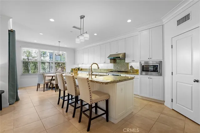 a kitchen with kitchen island granite countertop a counter space dining table and stainless steel appliances