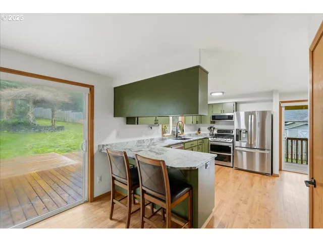 a open kitchen with stainless steel appliances kitchen island granite countertop a table chairs and a refrigerator
