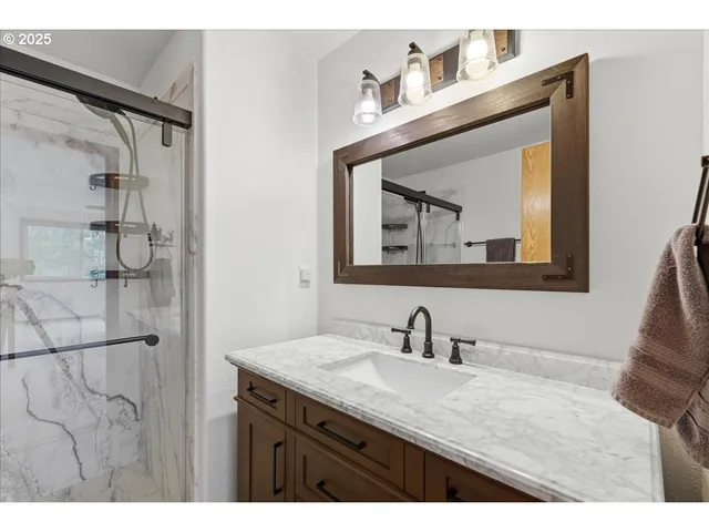 a bathroom with a granite countertop sink a mirror and shower