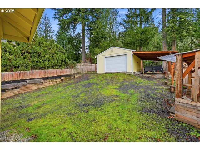 a view of a backyard with large trees and wooden fence