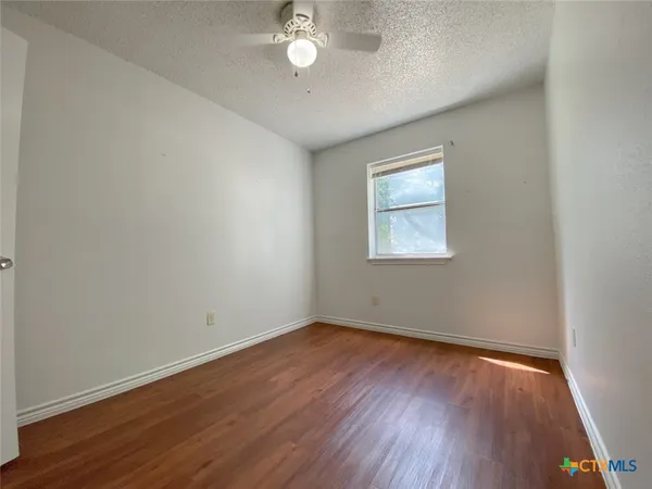 a view of an empty room with wooden floor and closet