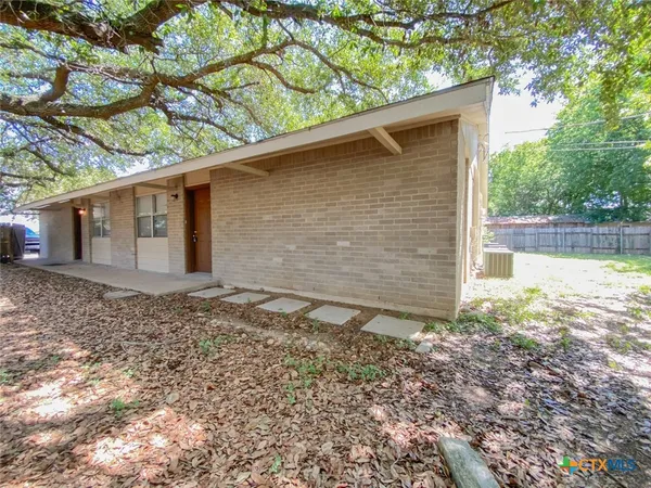 a backyard of a house with a yard and large tree