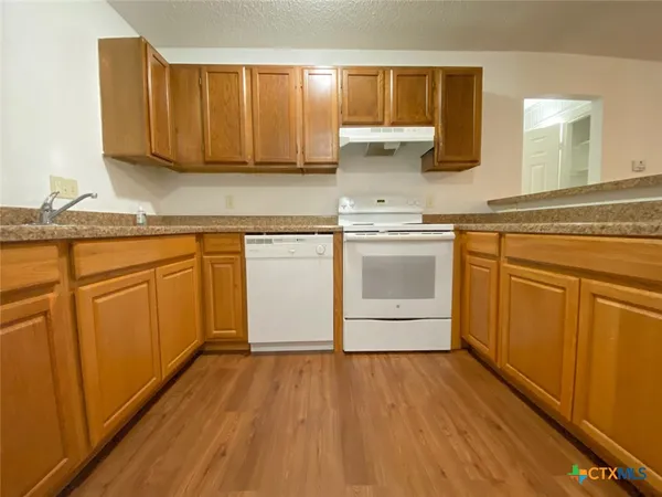 a kitchen with stainless steel appliances granite countertop wooden cabinets a sink and dishwasher a stove with wooden floor
