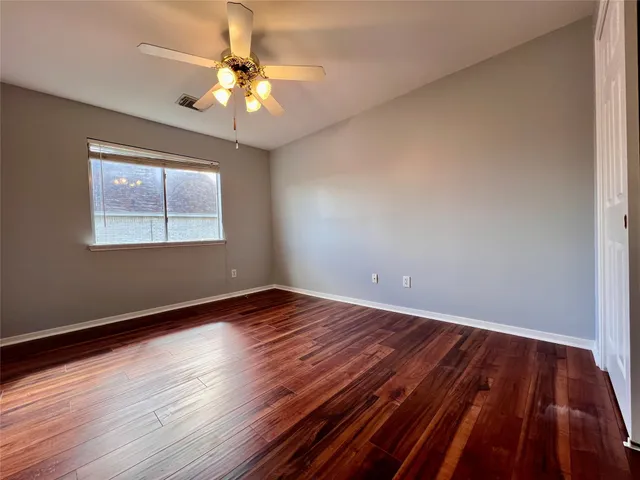 a view of empty room with wooden floor and fan