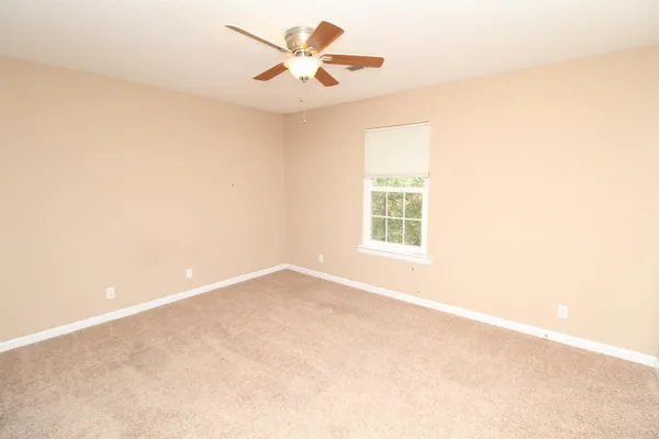 an empty room with a window and a ceiling fan