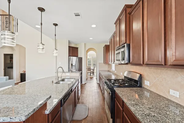 a kitchen with stainless steel appliances granite countertop a sink refrigerator and cabinets