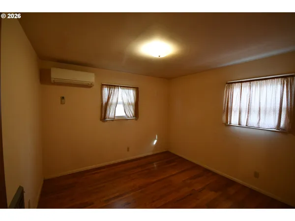 a view of an empty room with wooden floor and closet