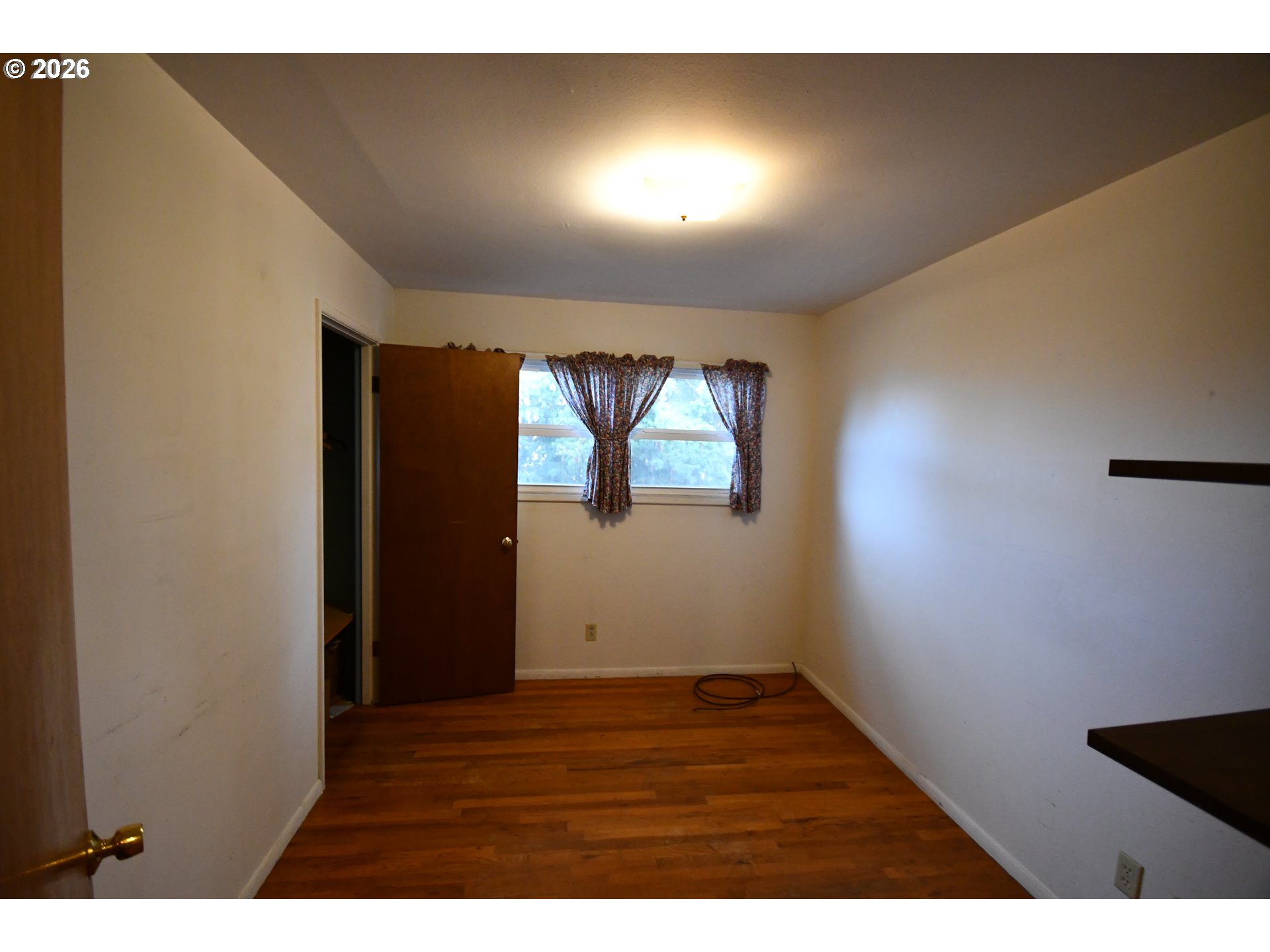 731 East 19th Street The Dalles, OR 97058 - Photo 37 of 42 a view of an empty room with wooden floor and a window