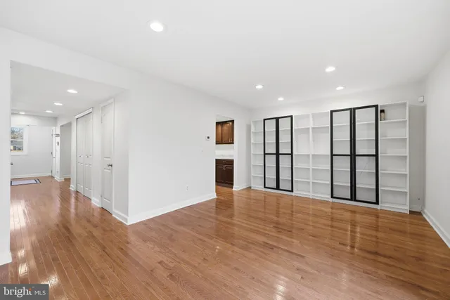 a view of an empty room with wooden floor and windows