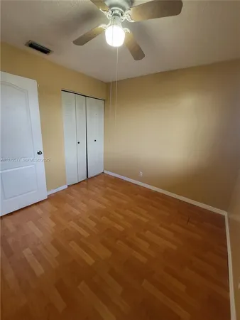 an empty room with a chandelier fan and windows