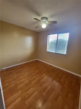 a view of an empty room with window and chandelier fan