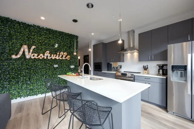 a kitchen with a sink a refrigerator and chairs
